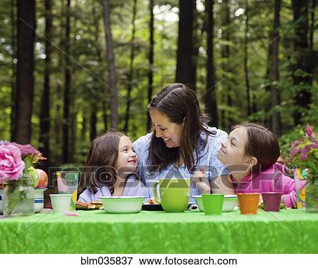 Caucasian mother and daughters sitting at table outdoors View Large Photo Image Stock Photo - Caucasian mother and daughters sitting at table outdoors. Fotosearch