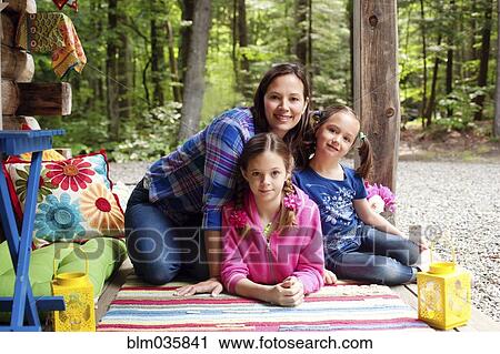 Stock Image - Caucasian mother and daughters smiling on porch. Fotosearch