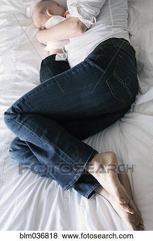 Caucasian mother cradling daughter on bed View Large Photo Image Stock Photo - Caucasian mother cradling daughter on bed. Fotosearch