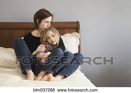 Caucasian mother cuddling daughter on sofa View Large Photo Image Stock Photo - Caucasian mother cuddling daughter on sofa. Fotosearch