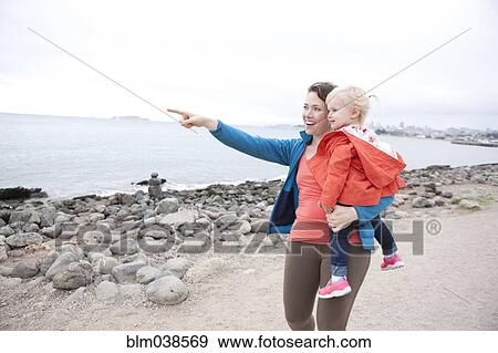 Caucasian mother holding daughter and pointing on beach View Large Photo Image Stock Photo - Caucasian mother holding daughter and pointing on beach. Fotosearch