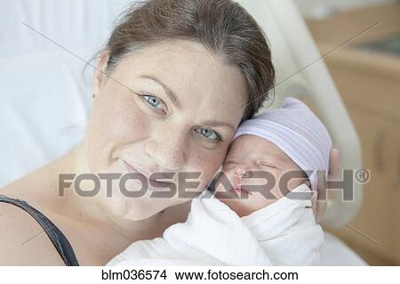 Caucasian mother holding newborn daughter in hospital bed View Large Photo Image Picture - Caucasian mother holding newborn daughter in hospital bed. Fotosearch