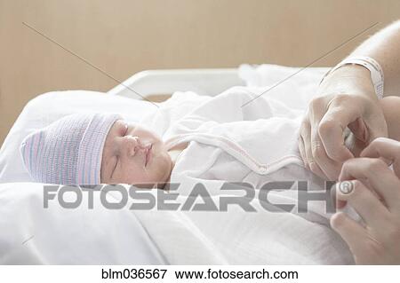 Stock Photo - Caucasian mother holding newborn daughter in hospital bed. Fotosearch