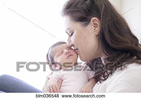 Stock Photo - Caucasian mother kissing baby girl. Fotosearch