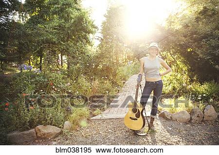 Caucasian musician holding guitar in park View Large Photo Image Stock Photography - Caucasian musician holding guitar in park. Fotosearch