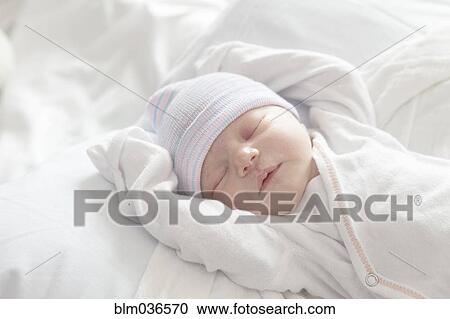 Stock Image - Caucasian newborn girl laying on bed. Fotosearch