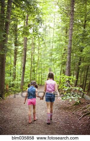 Stock Photo - Caucasian sisters walking in forest. Fotosearch