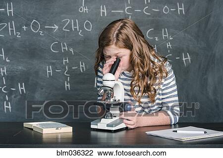 Stock Image - Caucasian student using microscope in science class. Fotosearch