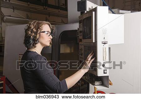 Stock Image - Caucasian technician operating machinery in warehouse. Fotosearch