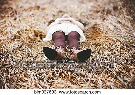 Stock Image - Caucasian teenage girl laying in tall grass. Fotosearch