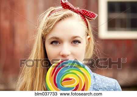 Stock Image - Caucasian teenage girl licking lollipop. Fotosearch