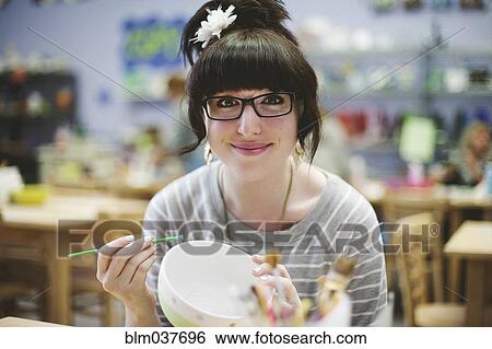 Stock Photograph - Caucasian teenage girl painting pottery in class. Fotosearch