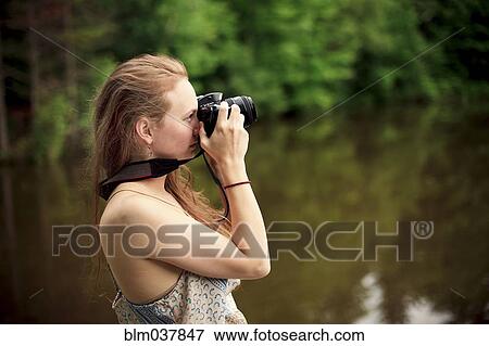 Stock Photo - Caucasian teenage girl photographing lake. Fotosearch
