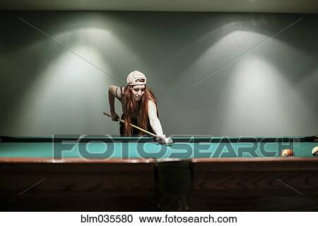 Stock Image - Caucasian teenage girl playing pool. Fotosearch
