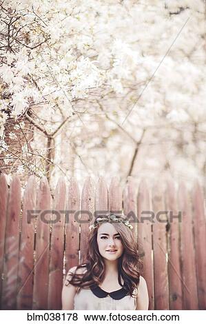 Stock Photo - Caucasian teenage girl wearing flower crown near wooden fence. Fotosearch