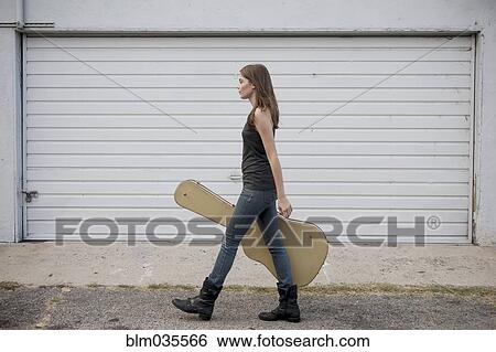 Caucasian woman carrying guitar case on sidewalk View Large Photo Image Stock Photograph - Caucasian woman carrying guitar case on sidewalk. Fotosearch