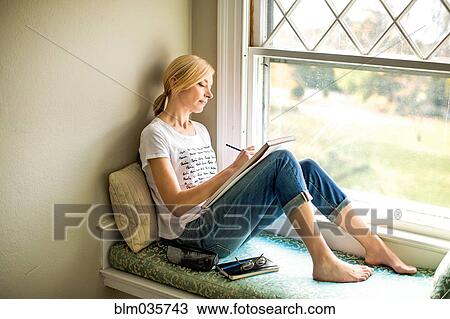 Stock Image - Caucasian woman drawing in windowsill. Fotosearch