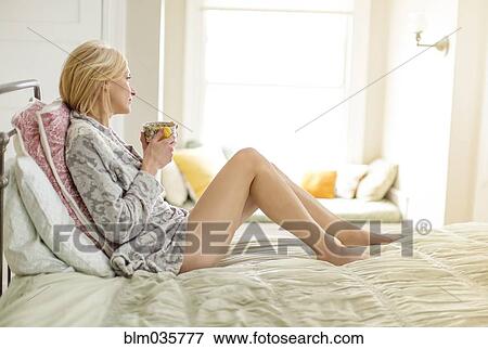 Caucasian woman drinking cup of coffee in bed View Large Photo Image Stock Photo - Caucasian woman drinking cup of coffee in bed. Fotosearch