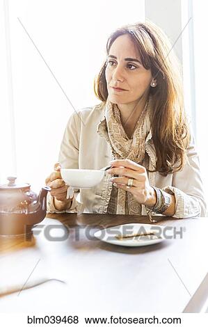 Stock Photo - Caucasian woman drinking tea at table. Fotosearch
