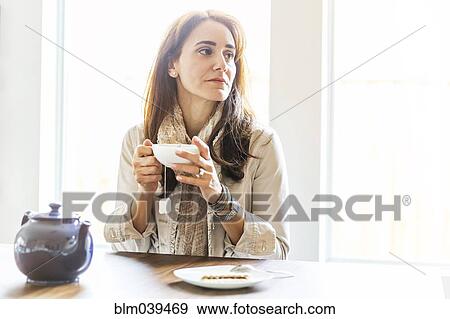 Stock Photo - Caucasian woman drinking tea at table. Fotosearch