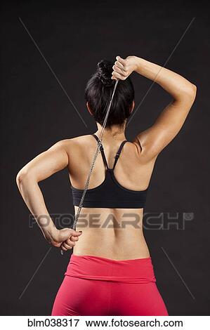 Stock Photo - Caucasian woman exercising with rope behind back. Fotosearch