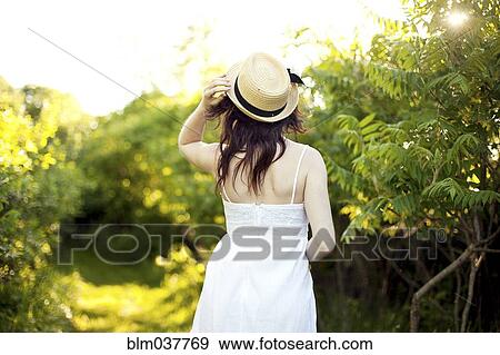Caucasian woman holding hat on rural path View Large Photo Image Stock Photo - Caucasian woman holding hat on rural path. Fotosearch