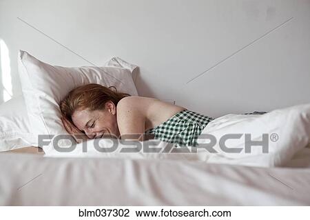 Stock Image - Caucasian woman laying in bed. Fotosearch