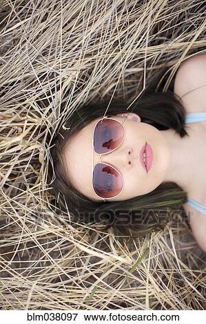 Stock Photo - Caucasian woman laying in hay. Fotosearch