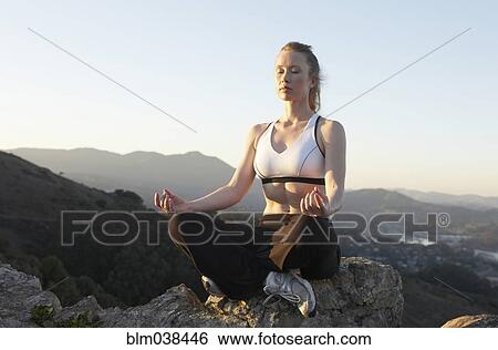 Stock Photograph - Caucasian woman meditating on mountaintop. Fotosearch