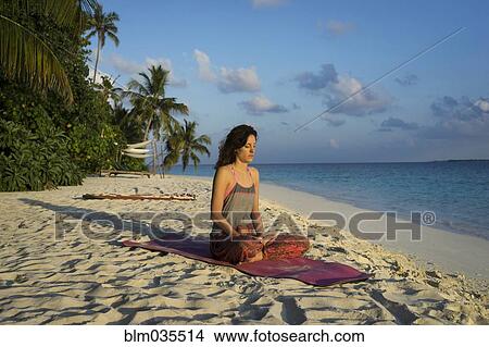 Picture - Caucasian woman meditating on tropical beach. Fotosearch