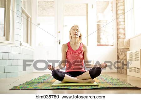 Stock Image - Caucasian woman meditating on yoga mat. Fotosearch