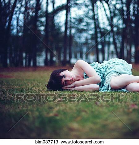 Stock Image - Caucasian woman napping in empty park. Fotosearch