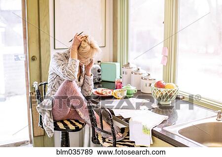Caucasian woman paying bills on telephone in kitchen View Large Photo Image Stock Photo - Caucasian woman paying bills on telephone in kitchen. Fotosearch