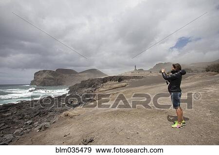 Caucasian woman photographing rocky beach View Large Photo Image Stock Photo - Caucasian woman photographing rocky beach. Fotosearch
