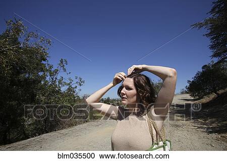 Caucasian woman pinning her hair on dirt path View Large Photo Image Stock Image - Caucasian woman pinning her hair on dirt path. Fotosearch