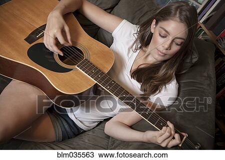 Caucasian woman playing guitar on sofa View Large Photo Image Stock Image - Caucasian woman playing guitar on sofa. Fotosearch
