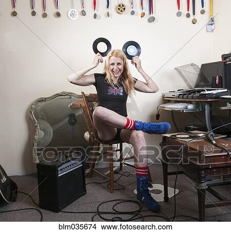 Picture - Caucasian woman playing with vinyl records in living room. Fotosearch