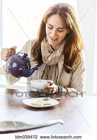 Caucasian woman pouring cup of tea at table View Large Photo Image Stock Image - Caucasian woman pouring cup of tea at table. Fotosearch
