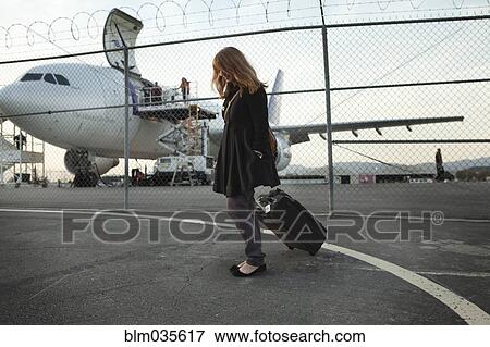 Stock Photo - Caucasian woman pulling luggage at airport. Fotosearch