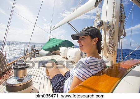 Stock Image - Caucasian woman relaxing on sailboat deck. Fotosearch
