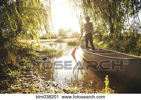 Stock Image - Caucasian woman rowing canoe in rural creek. Fotosearch