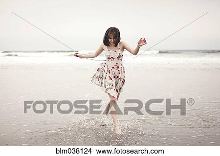 Picture - Caucasian woman running in waves on beach. Fotosearch
