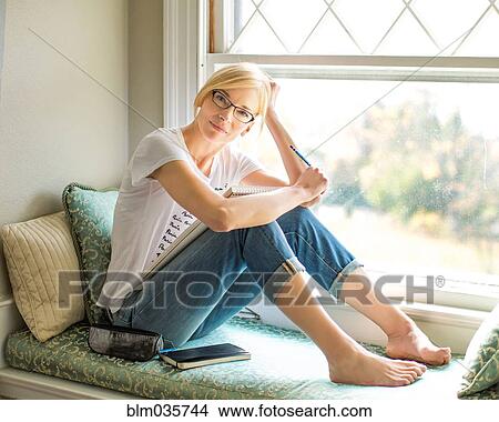 Picture - Caucasian woman sitting in windowsill. Fotosearch