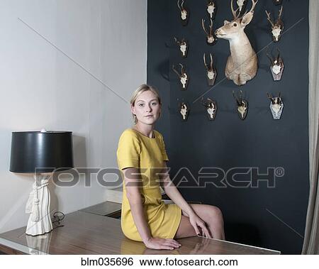 Caucasian woman sitting on desk View Large Photo Image Stock Photograph - Caucasian woman sitting on desk. Fotosearch