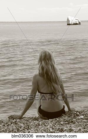 Caucasian woman sitting on rocky beach View Large Photo Image Stock Photograph - Caucasian woman sitting on rocky beach. Fotosearch