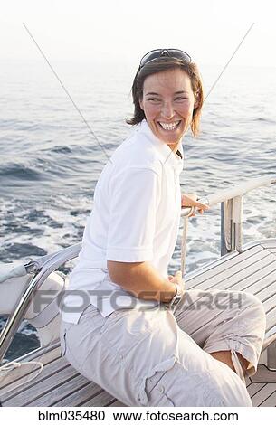 Stock Image - Caucasian woman smiling on boat deck. Fotosearch