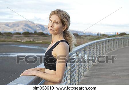 Stock Image - Caucasian woman standing on footbridge. Fotosearch