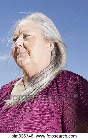 Stock Photograph - Caucasian woman standing under blue sky. Fotosearch