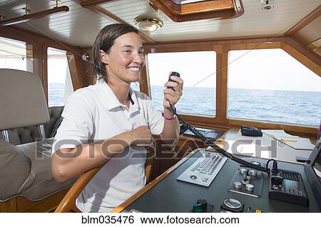 Stock Photograph - Caucasian woman steering boat and using radio. Fotosearch