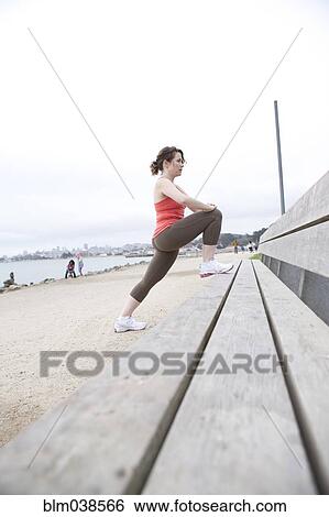 Caucasian woman stretching on beach bench View Large Photo Image Stock Photograph - Caucasian woman stretching on beach bench. Fotosearch